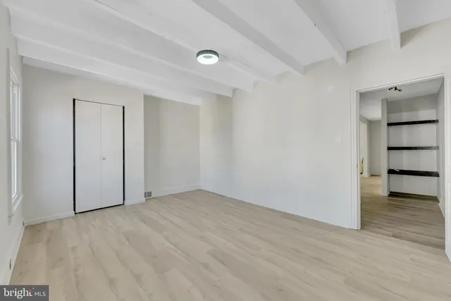 a view of an empty room with wooden floor and closet