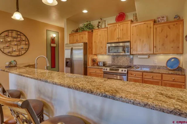 a kitchen with stainless steel appliances granite countertop a sink and a refrigerator