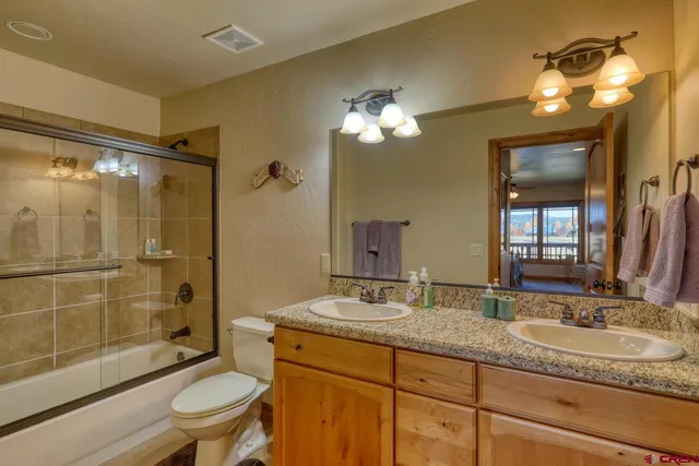 a bathroom with a granite countertop sink toilet a mirror and shower
