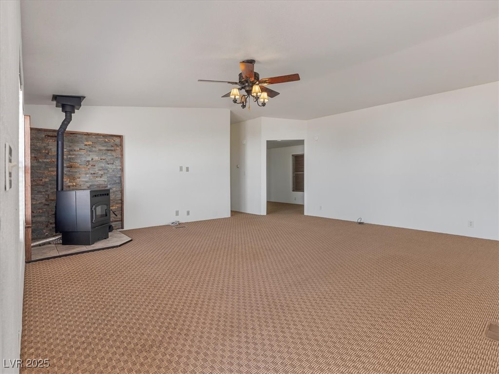 70 West Bonanza Road Las Vegas, NV 89124 - Photo 11 of 71 Unfurnished living room with carpet, a wood stove, and ceiling fan