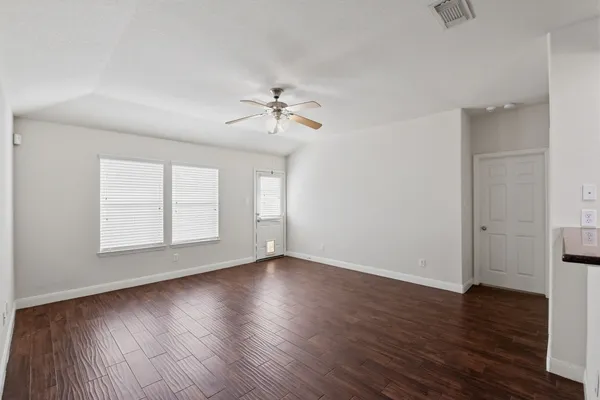 a view of an empty room with a window and wooden floor