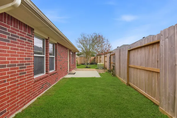 a view of a backyard with brick wall and a large tree