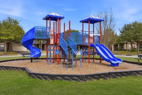 a view of a lake with lawn chairs and large trees