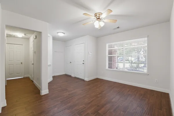 a view of an empty room with a window and wooden floor