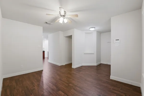 an empty room with wooden floor and chandelier fan