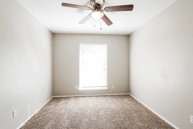 an empty room with chandelier fan and windows