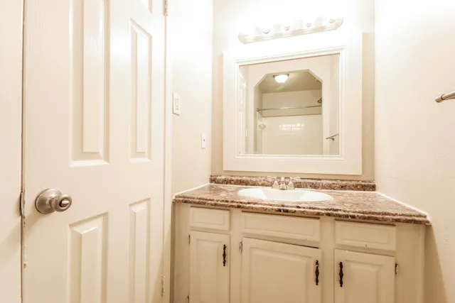 a bathroom with a granite countertop sink and a mirror
