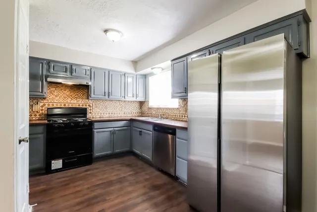 a kitchen with granite countertop stainless steel appliances a refrigerator and cabinets