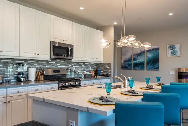 a kitchen with sink a stove and white cabinets with wooden floor
