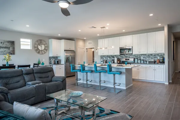 a living room with stainless steel appliances furniture and a kitchen view