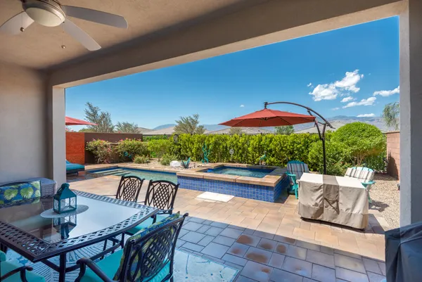 a view of a patio with couches table and chairs under an umbrella