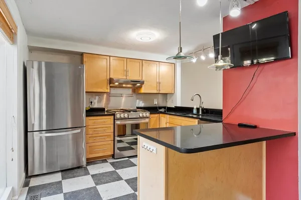a kitchen with stainless steel appliances granite countertop a refrigerator a stove and a sink with wooden floor