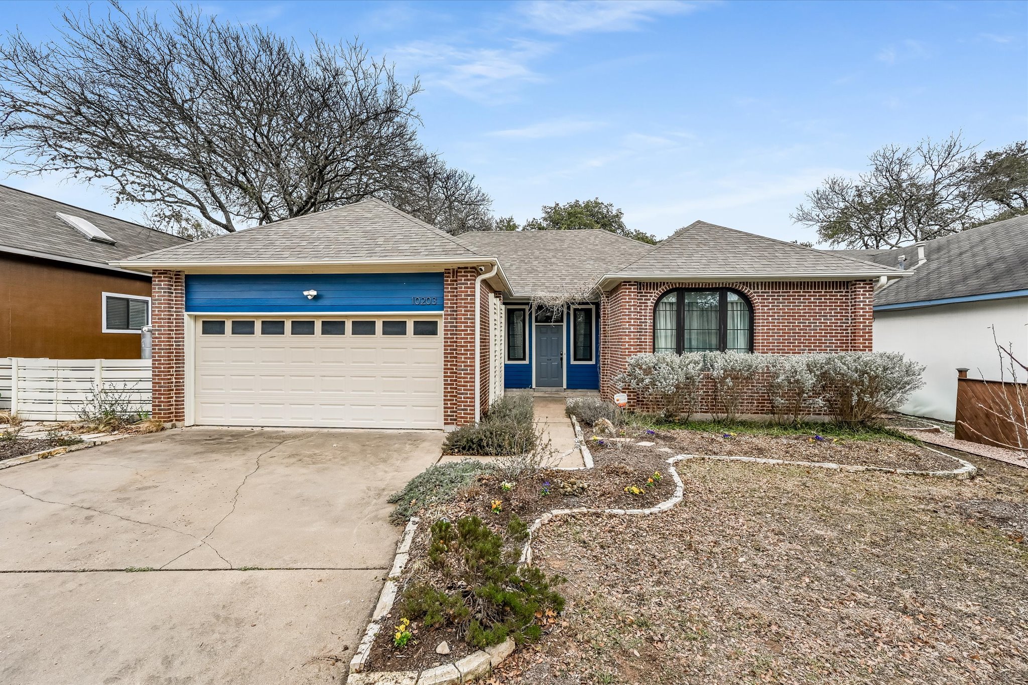 Ranch-style home featuring roof with shingles, driveway, and brick siding
