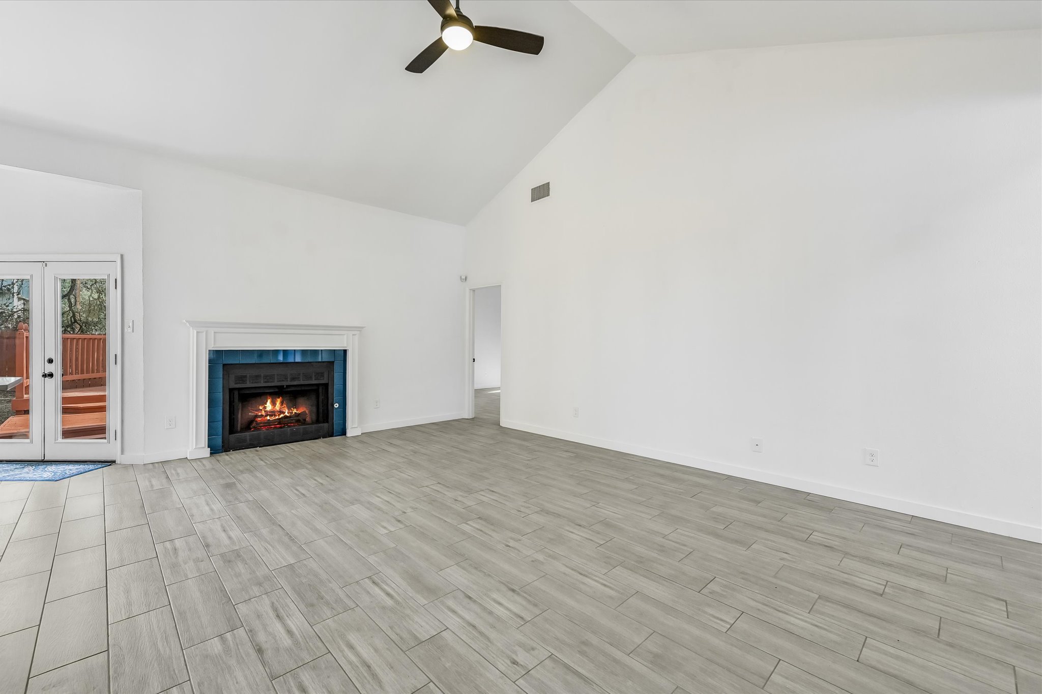 10203 Brantley Bend Austin, TX 78748 - Photo 4 of 20 Unfurnished living room with a ceiling fan, vaulted ceiling, french doors, wood finish floors, and a tile fireplace