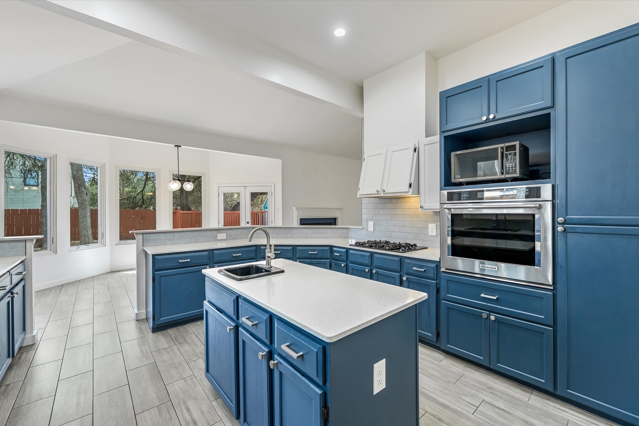 10203 Brantley Bend Austin, TX 78748 - Photo 7 of 20 Kitchen featuring stainless steel appliances, an island with sink, tasteful backsplash, light stone countertops, and wood finish floors