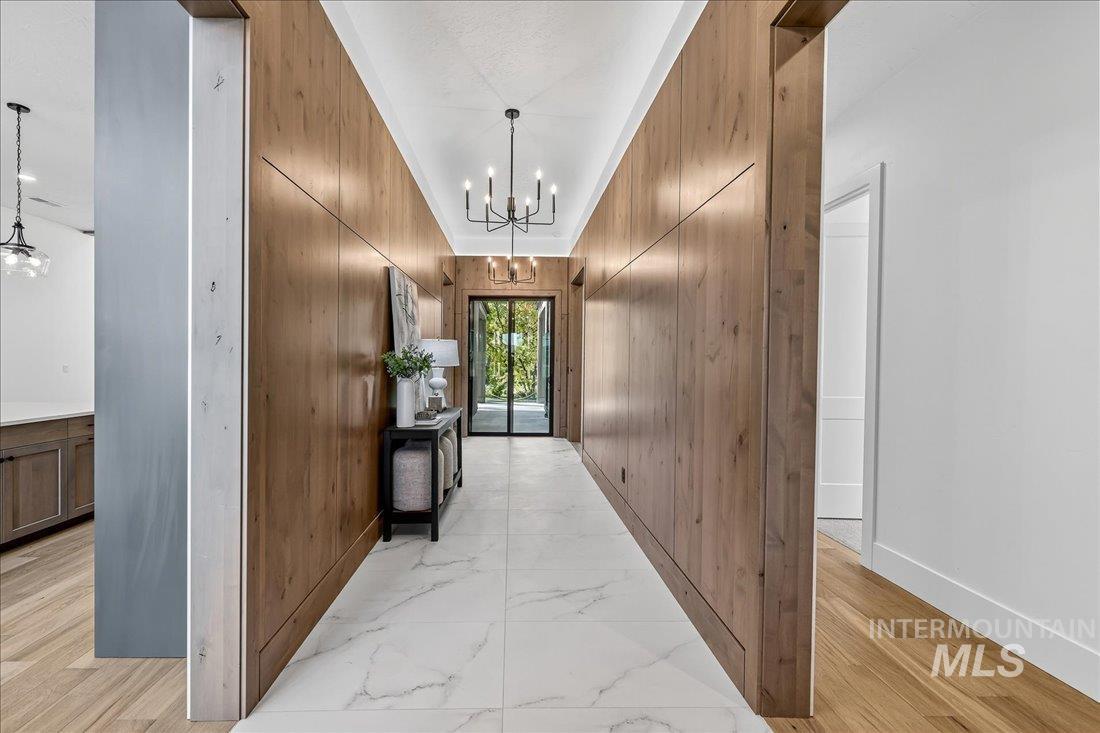 665 Watkins Street Middleton, ID 83644 - Photo 12 of 34 Hall with a chandelier, light marble finish floors, and wooden walls