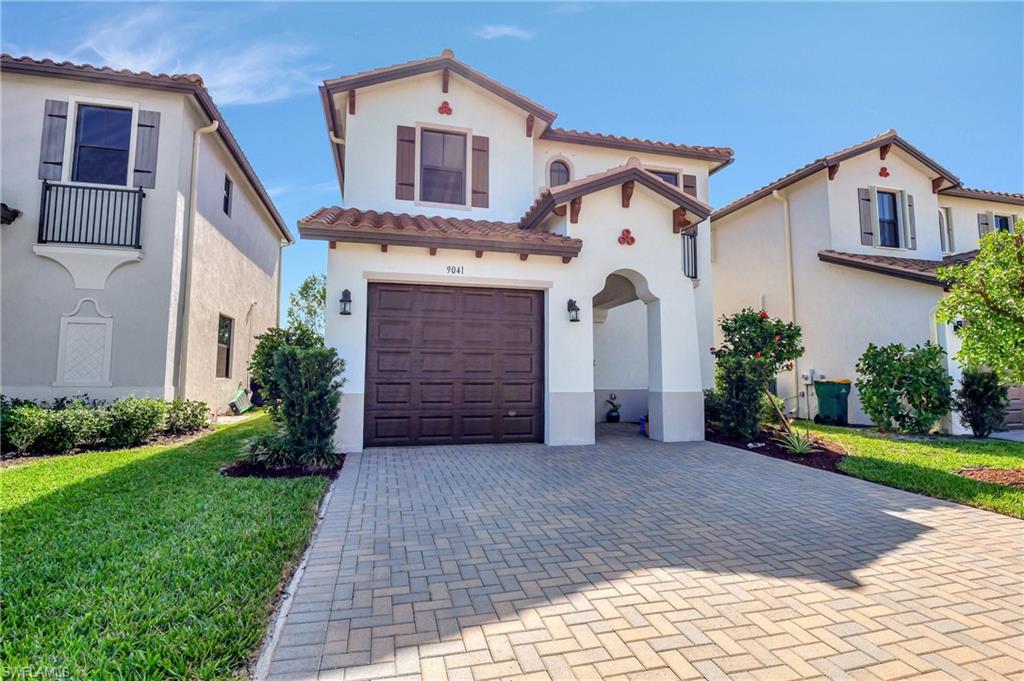 9041 Madrid Circle Naples, FL 34104 - Photo 1 of 32 a front view of a house with a yard and garage