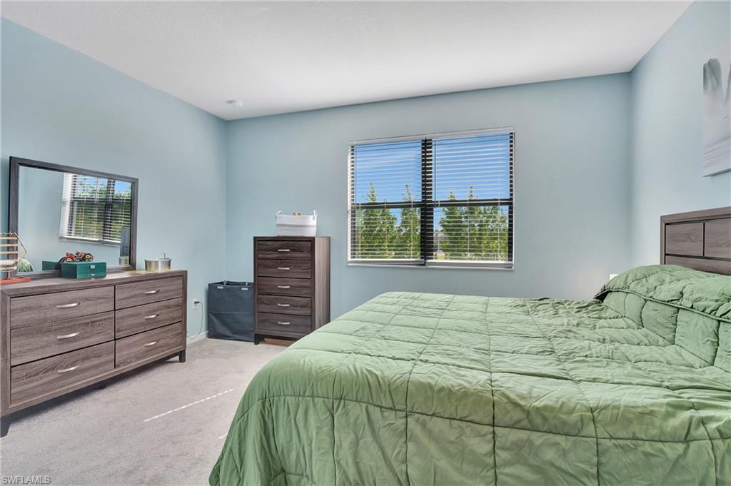 9041 Madrid Circle Naples, FL 34104 - Photo 11 of 32 a bedroom with a bed and a dresser