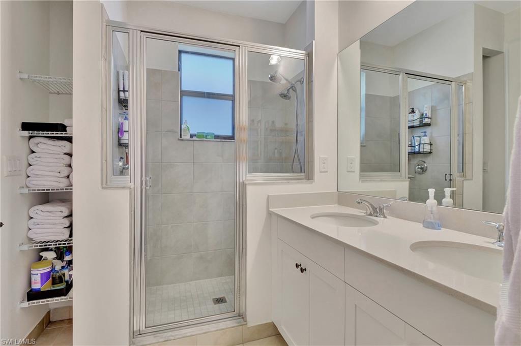 9041 Madrid Circle Naples, FL 34104 - Photo 13 of 32 a bathroom with a shower sink and mirror