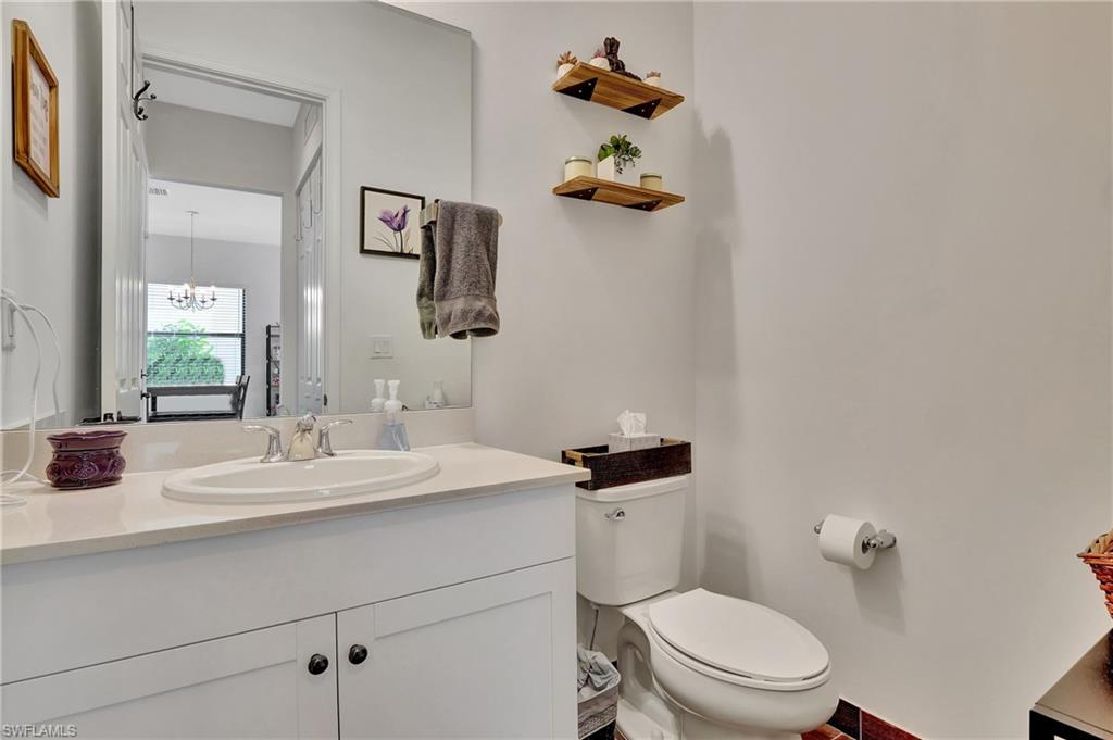 9041 Madrid Circle Naples, FL 34104 - Photo 17 of 32 a bathroom with a sink a toilet and mirror