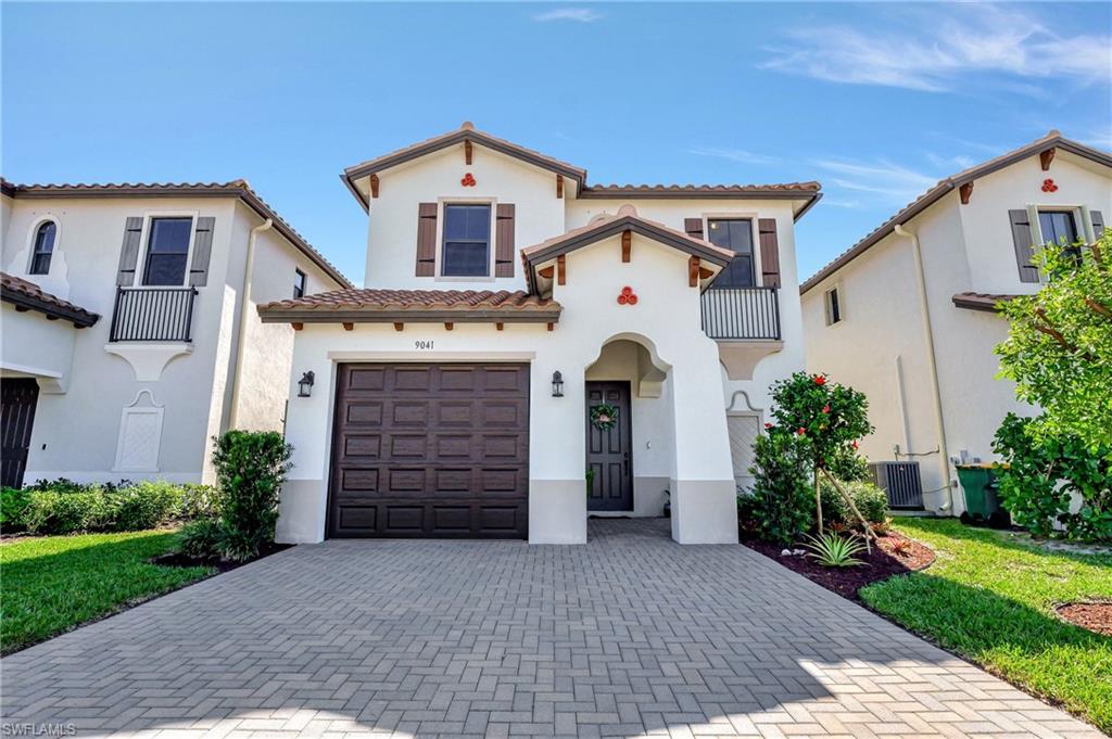 9041 Madrid Circle Naples, FL 34104 - Photo 2 of 32 a front view of a house with a yard and garage