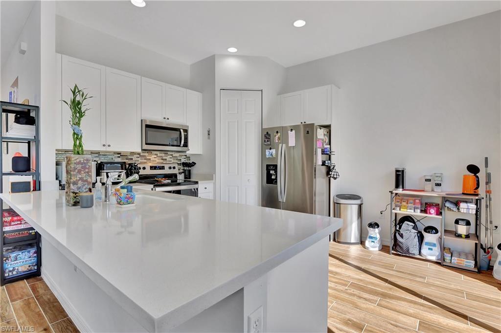 9041 Madrid Circle Naples, FL 34104 - Photo 26 of 32 a kitchen with stainless steel appliances a stove sink and a refrigerator