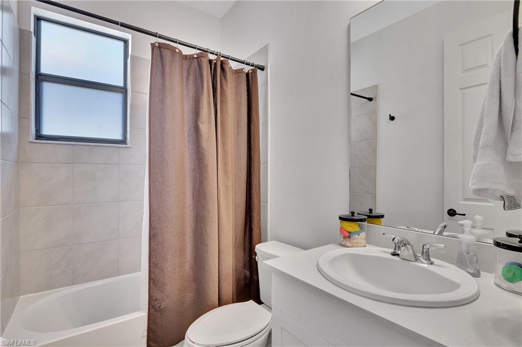 9041 Madrid Circle Naples, FL 34104 - Photo 5 of 32 a bathroom with a sink a toilet and shower