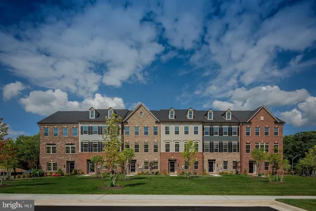 a view of a big yard in front of a brick house with large windows