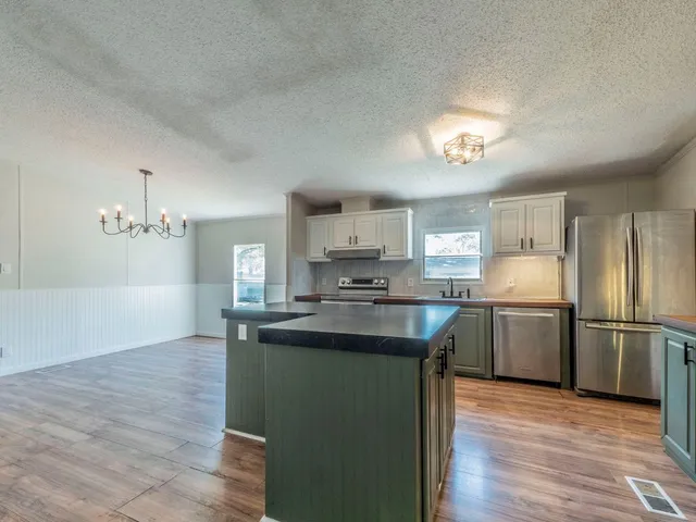 a kitchen with kitchen island granite countertop a sink cabinets and stainless steel appliances