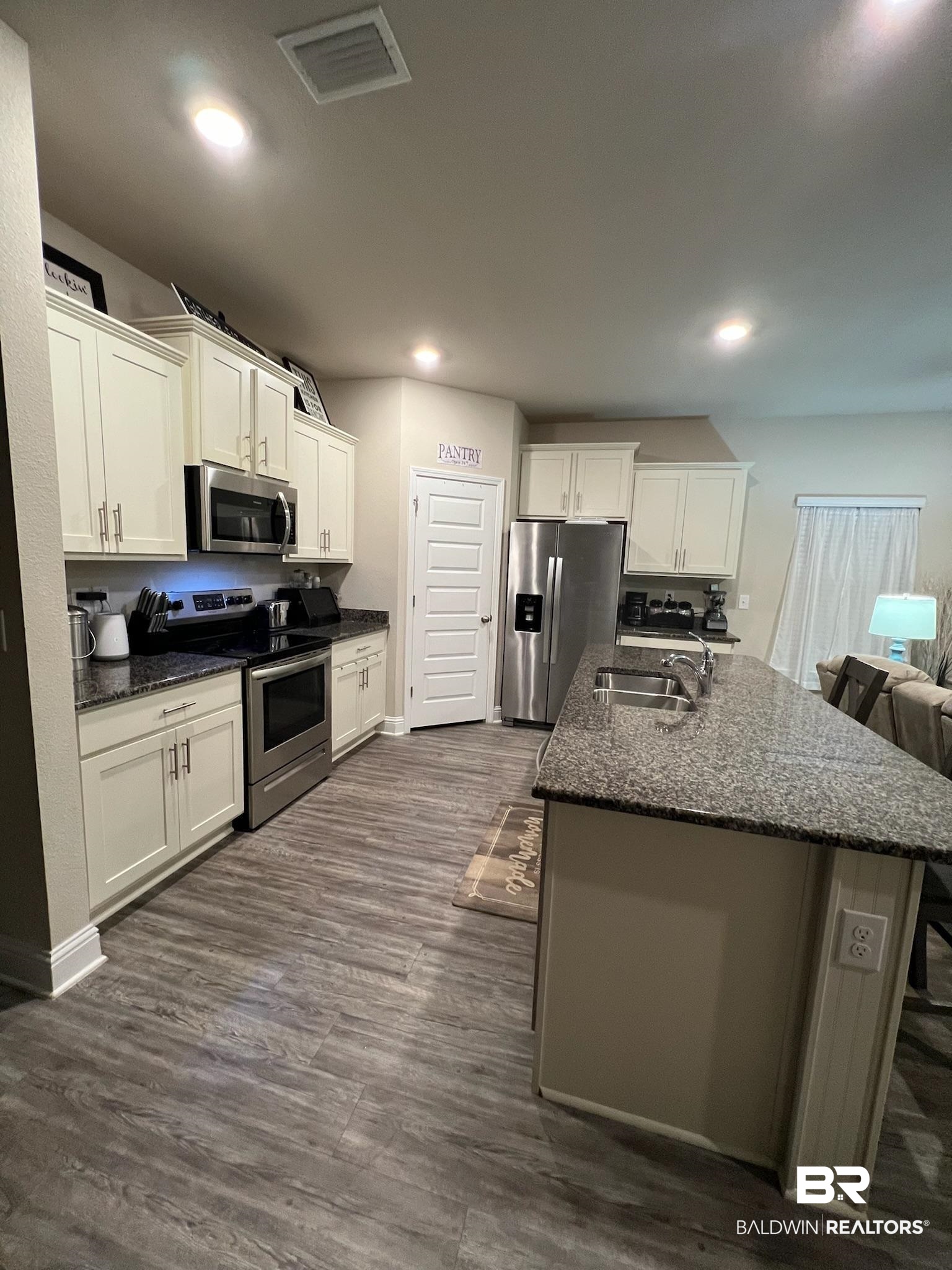 3904 Conrad Court Gulf Shores, AL 36542 - Photo 6 of 24 Kitchen featuring stainless steel appliances, white cabinetry, and dark hardwood / wood-style floors