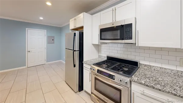 a kitchen with stainless steel appliances white cabinets and a stove top oven