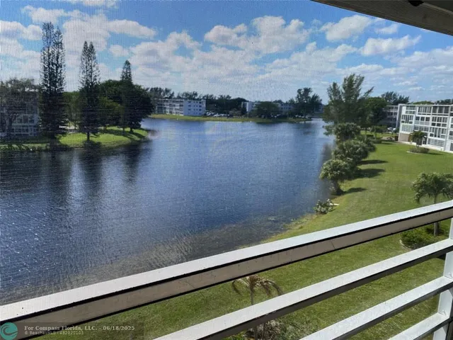 a kitchen with stainless steel appliances kitchen island granite countertop a stove a refrigerator a oven and white cabinets with wooden floor