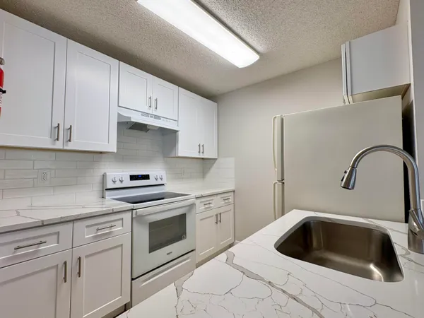 a kitchen with white cabinets a sink and dishwasher