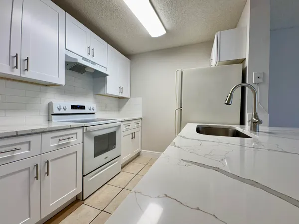 a kitchen with granite countertop white cabinets sink and stainless steel appliances