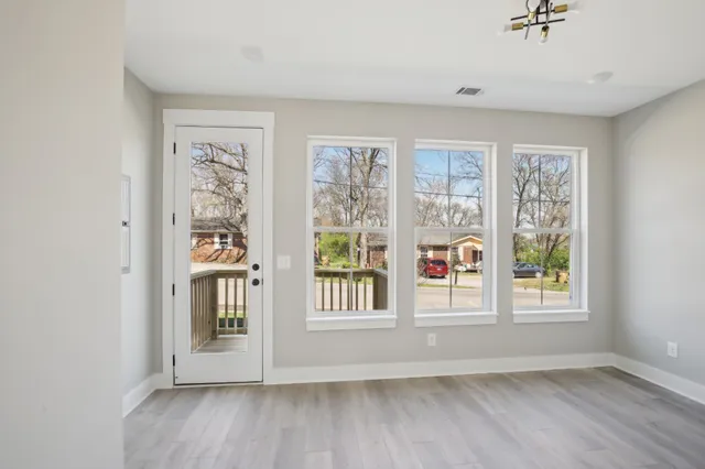 an empty room with wooden floor and windows