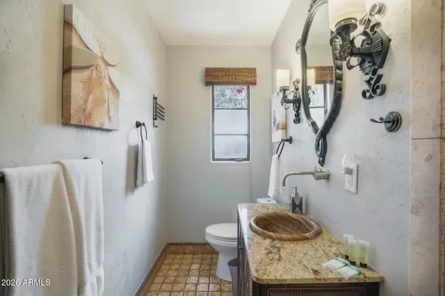 a bathroom with a granite countertop toilet and a sink