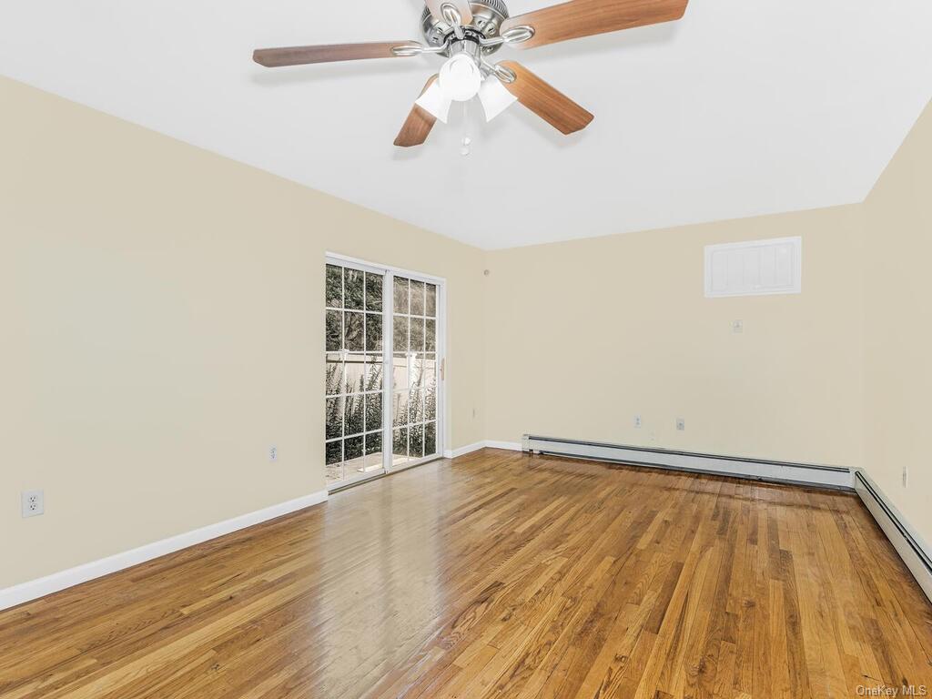 a view of an empty room with wooden floor and a ceiling fan