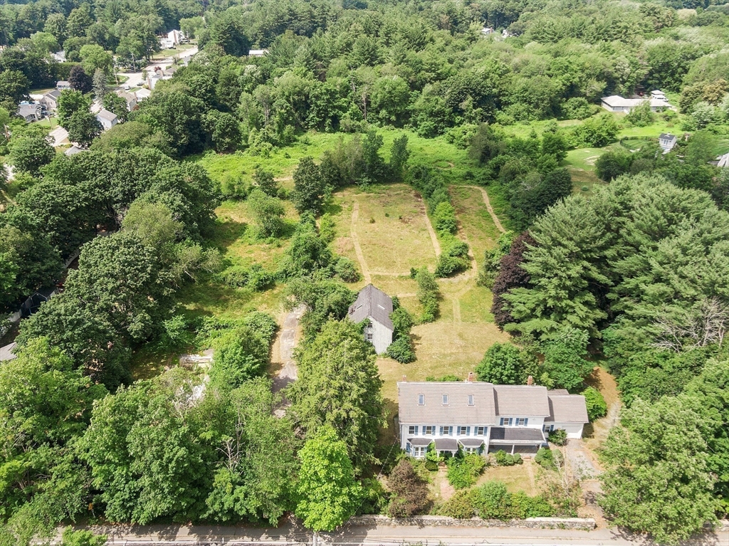 an aerial view of residential house with outdoor space and trees all around