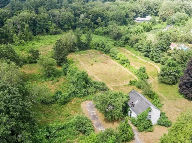 an aerial view of residential houses with outdoor space and trees