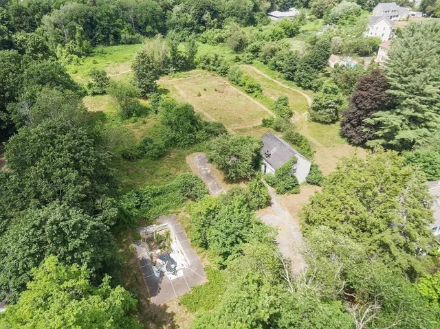 an aerial view of residential house with outdoor space and trees all around