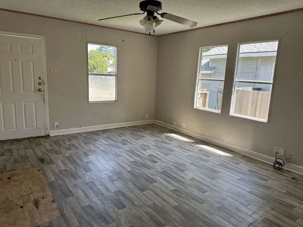 an empty room with wooden floor chandelier and windows