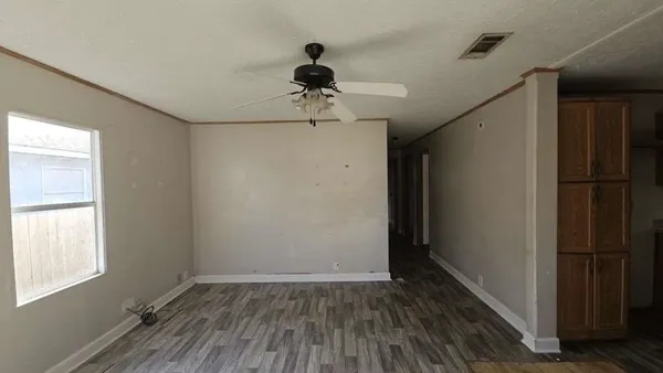 a view of empty room with wooden floor and fan