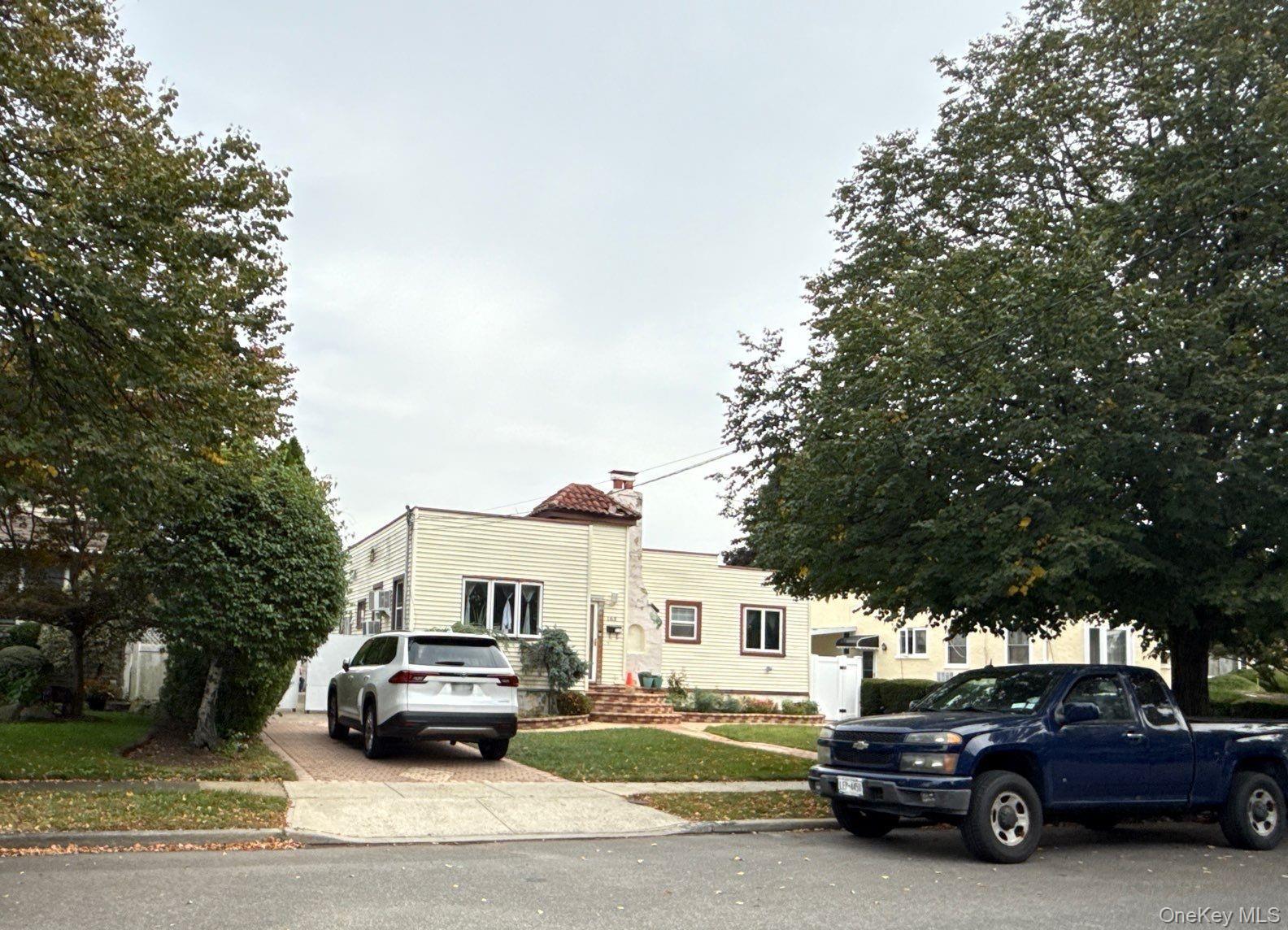 163 Wynsum Avenue Merrick, NY 11566 - Photo 2 of 3 a car parked in front of a white house