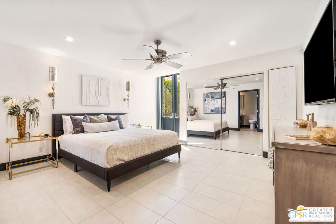 48365 Alan Circle Palm Desert, CA 92260 - Photo 54 of 75 a spacious bedroom with a bed a flat screen tv and chandelier