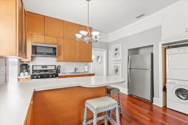 a kitchen with stainless steel appliances granite countertop a refrigerator a stove top oven a sink dishwasher and white cabinets with wooden floor