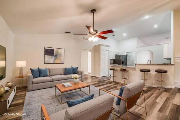 a living room with lots of furniture and a ceiling fan
