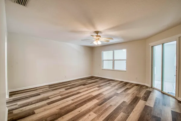a view of an empty room with window and wooden floor