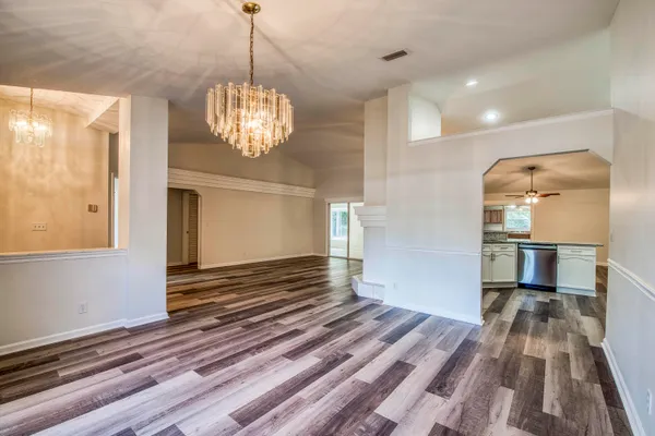 a view of a room with wooden floor staircase and a kitchen space