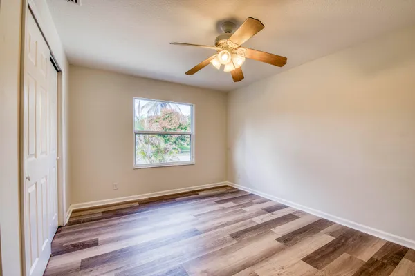 an empty room with wooden floor fan and windows