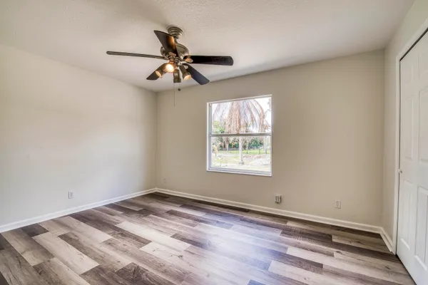 an empty room with wooden floor fan and windows